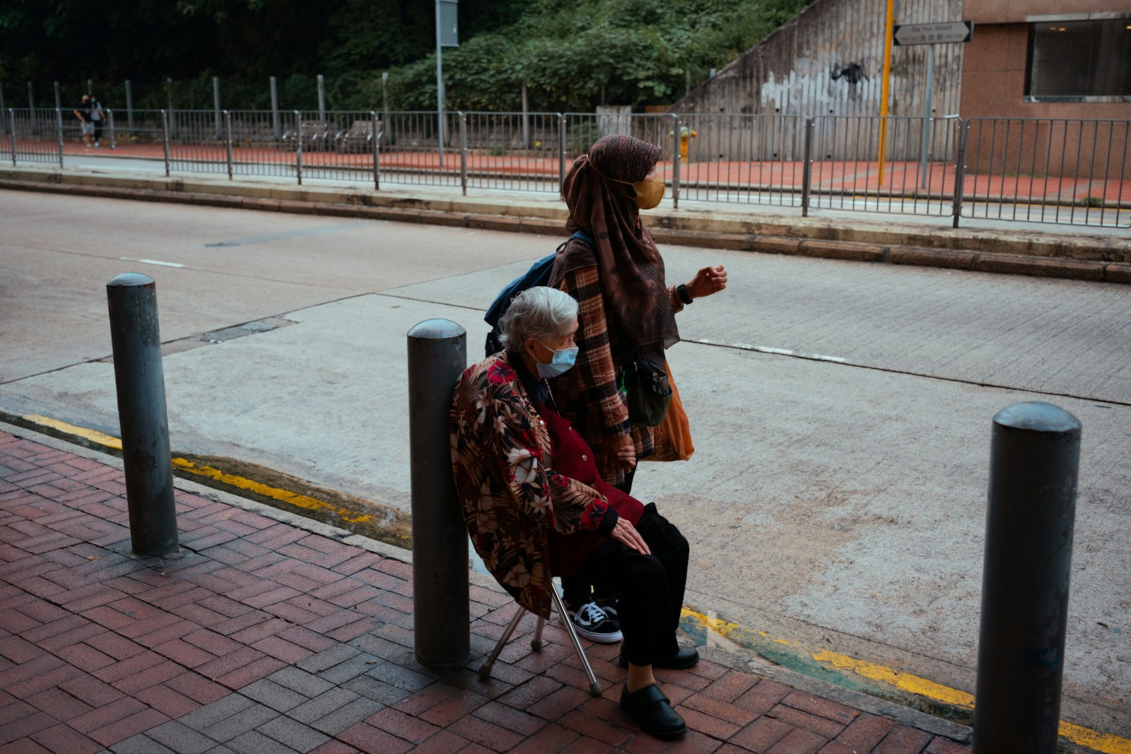 woman in brown leather jacket and black pants sitting on black steel bench during daytime