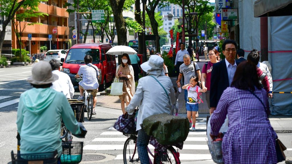 People crossing a busy street on a sunny day