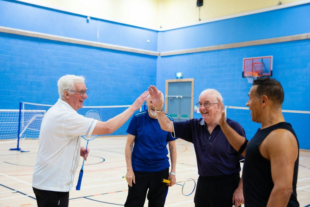 Four men playing badminton and giving high fives